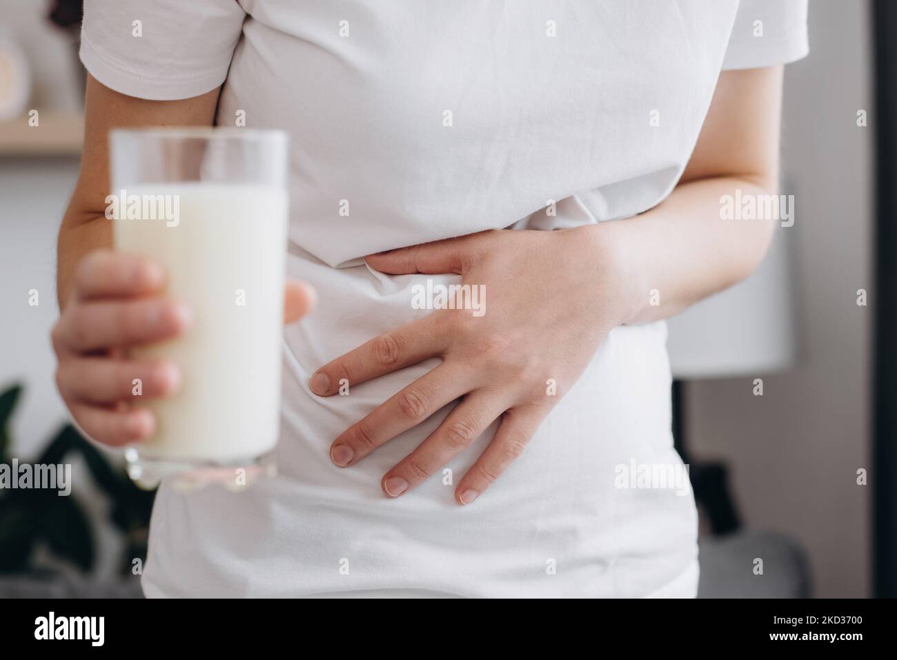 Close up of young woman holding glass milk feels bad, has an upset