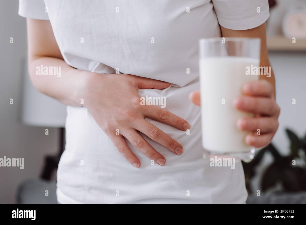 Close up of unhealthy young caucasian female holding glass of milk