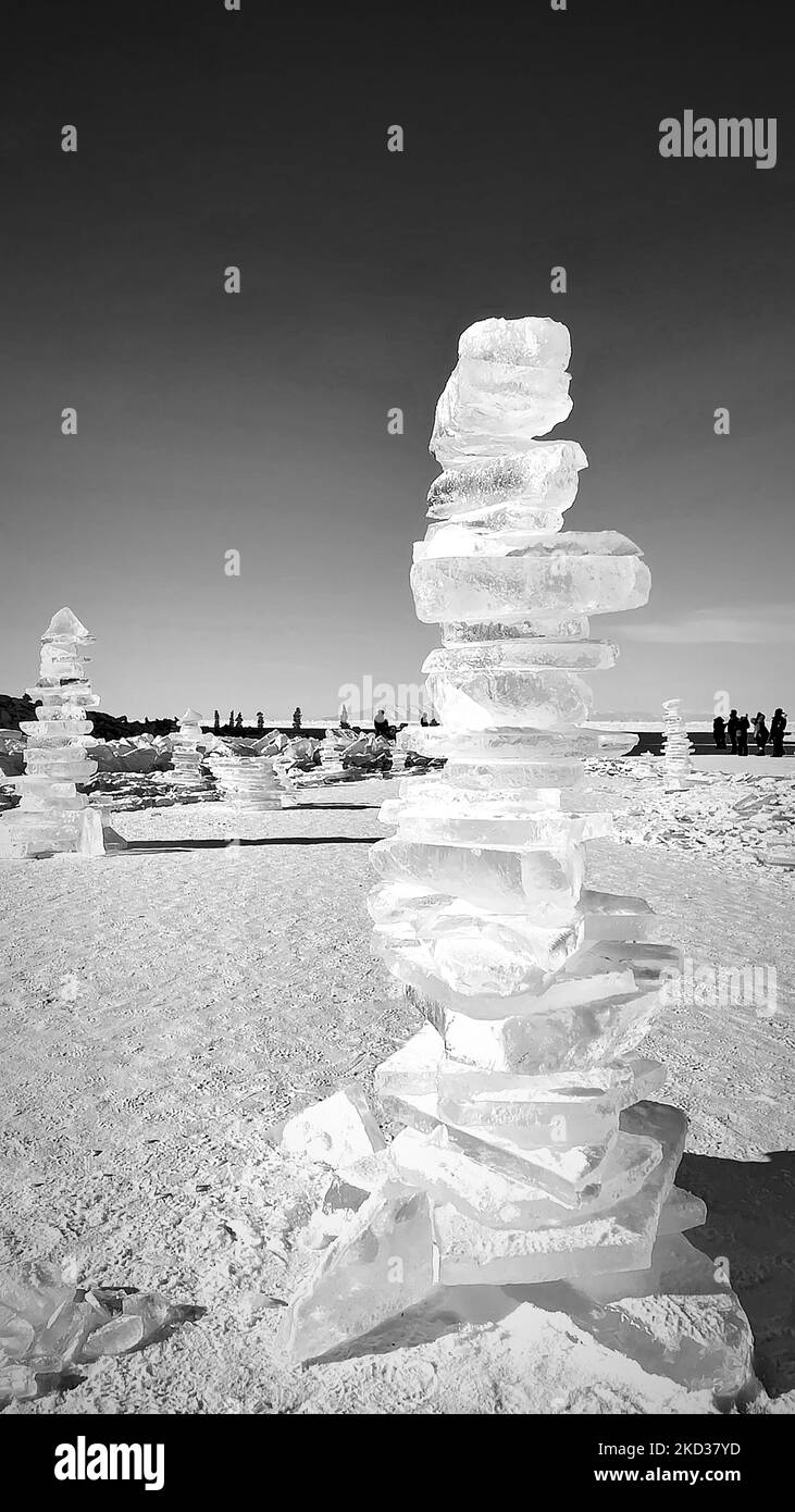 Pieces of ice lying on the ideal smooth ice of baikal with ice hummocks in the horizon. Sun is shining through the sides of ice cubes. Floes look like Stock Photo