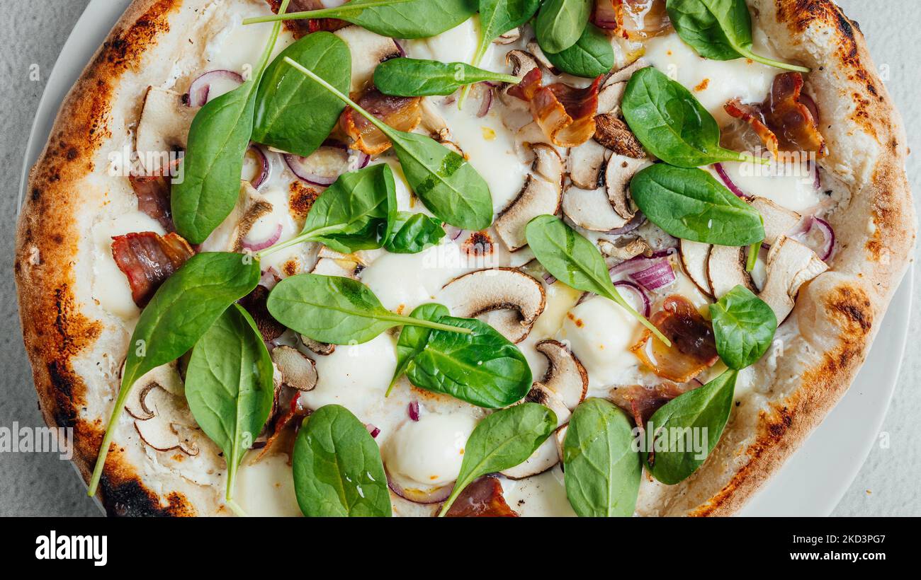 A top view of a pizza with mushrooms and greens on a table Stock Photo