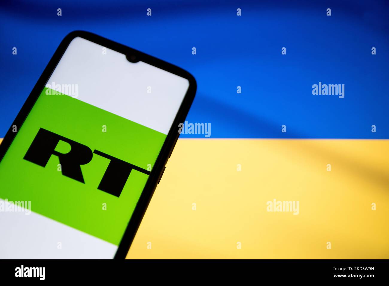 In this photo illustration a RT News logo seen displayed on a smartphone screen with a flag of Ukraine in the background in Athens, Greece on February 28, 2022. Google blocks Russia's RT News app downloads on Ukrainian territory. (Photo illustration by Nikolas Kokovlis/NurPhoto) Stock Photo