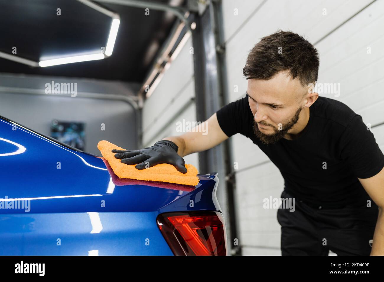 Cleaner man worker dry body car after washing automobile. Hand car