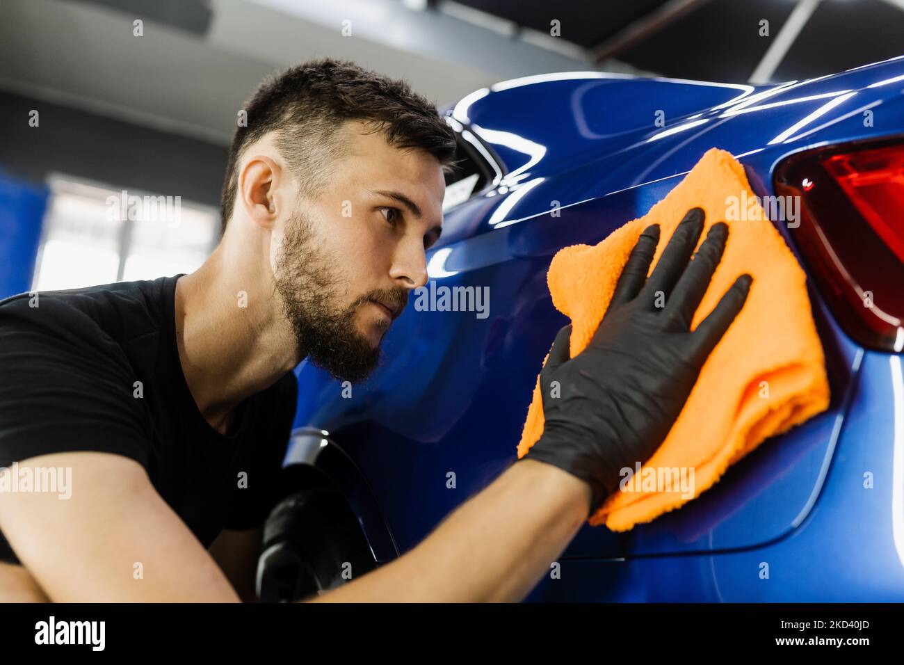 Cleaner man worker dry body car after washing automobile. Hand car