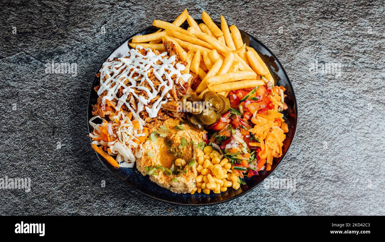 A top view of a mixed dish with fries, chicken, and veggies Stock Photo