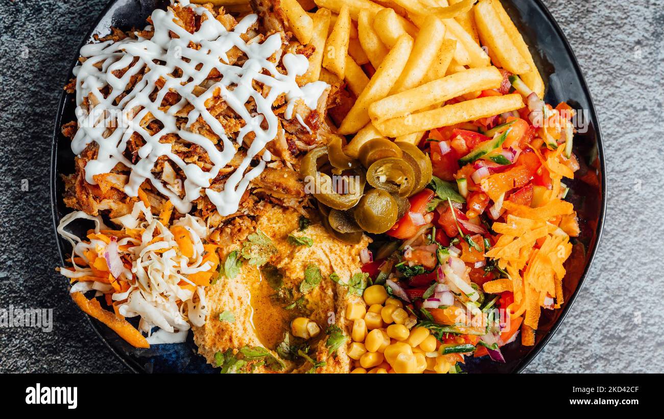 A top view of a mixed dish with fries, chicken, and veggies Stock Photo
