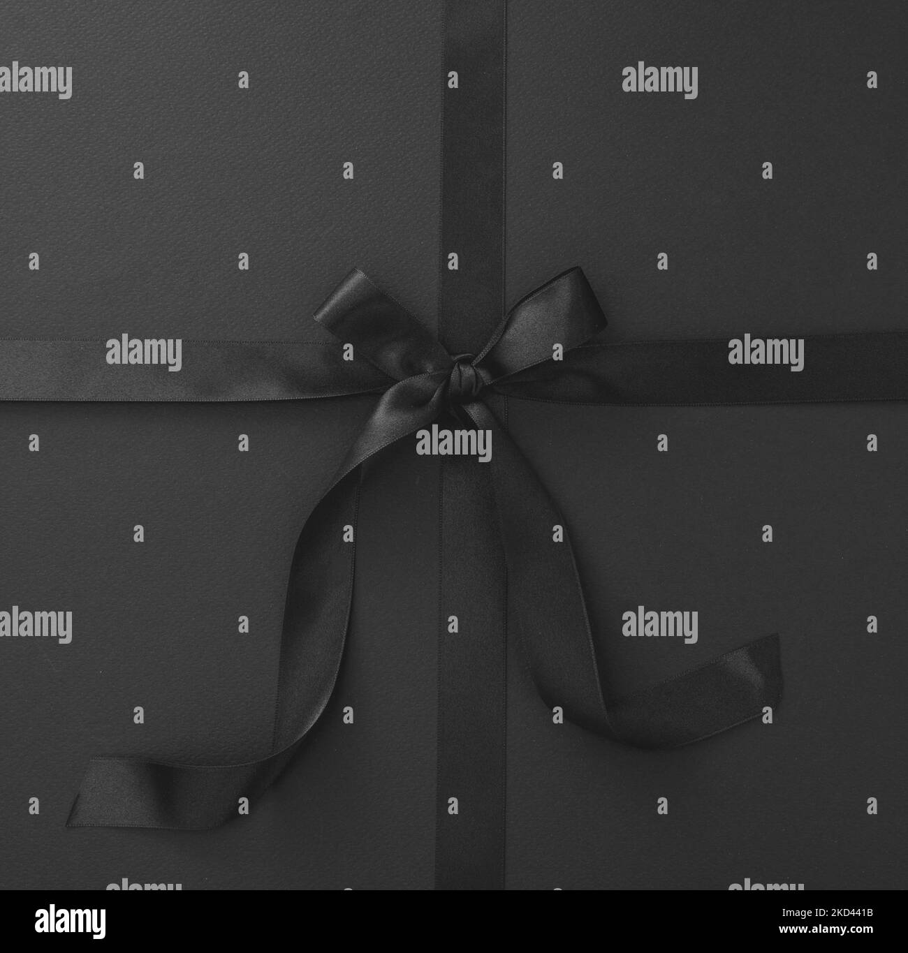 Black Friday sales promotion concept. Luxury black satin ribbon and tied bow on black background, top view. Advertising template Stock Photo