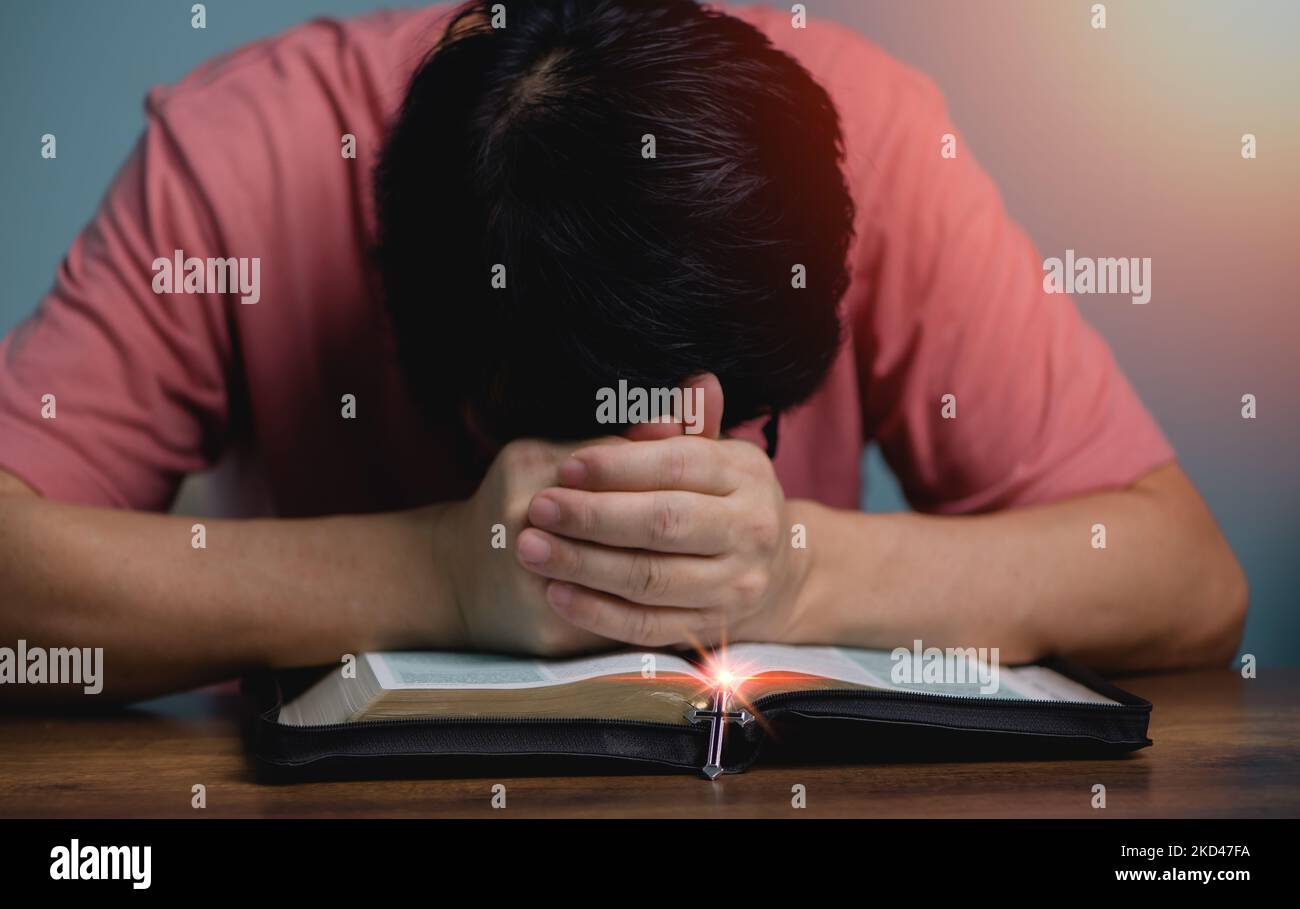 People holding hands head bow down pray to God in the middle book holy