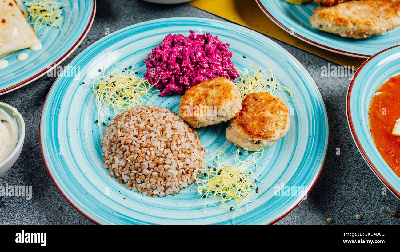 A blue plate with fishcakes and buckwheat grains with a side of Beetroot salad Stock Photo