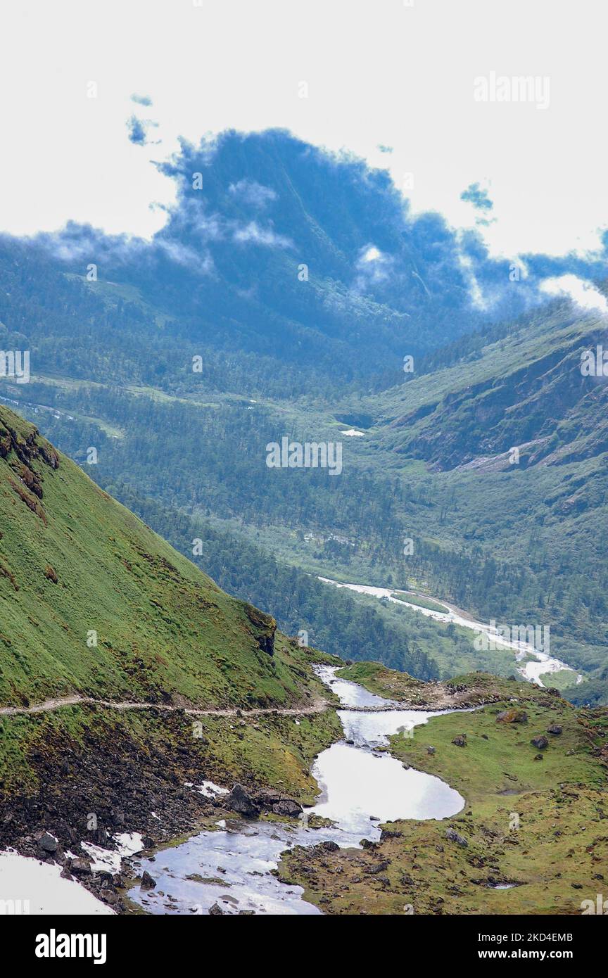 An aerial view of clouds hovering over a green filled valley with trees ...