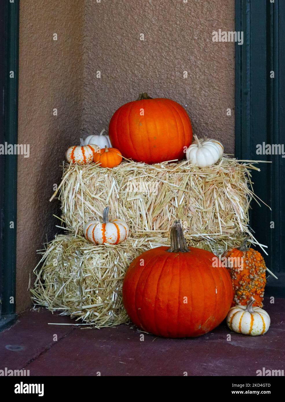 Variety of Pumpkins on Hay Bales - Fall Halloween Decor beside entrance of home Stock Photo