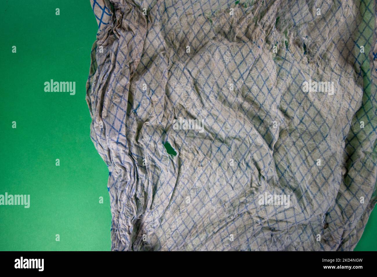 dirty and faded torn dish cloth isolated on a dark green background ...