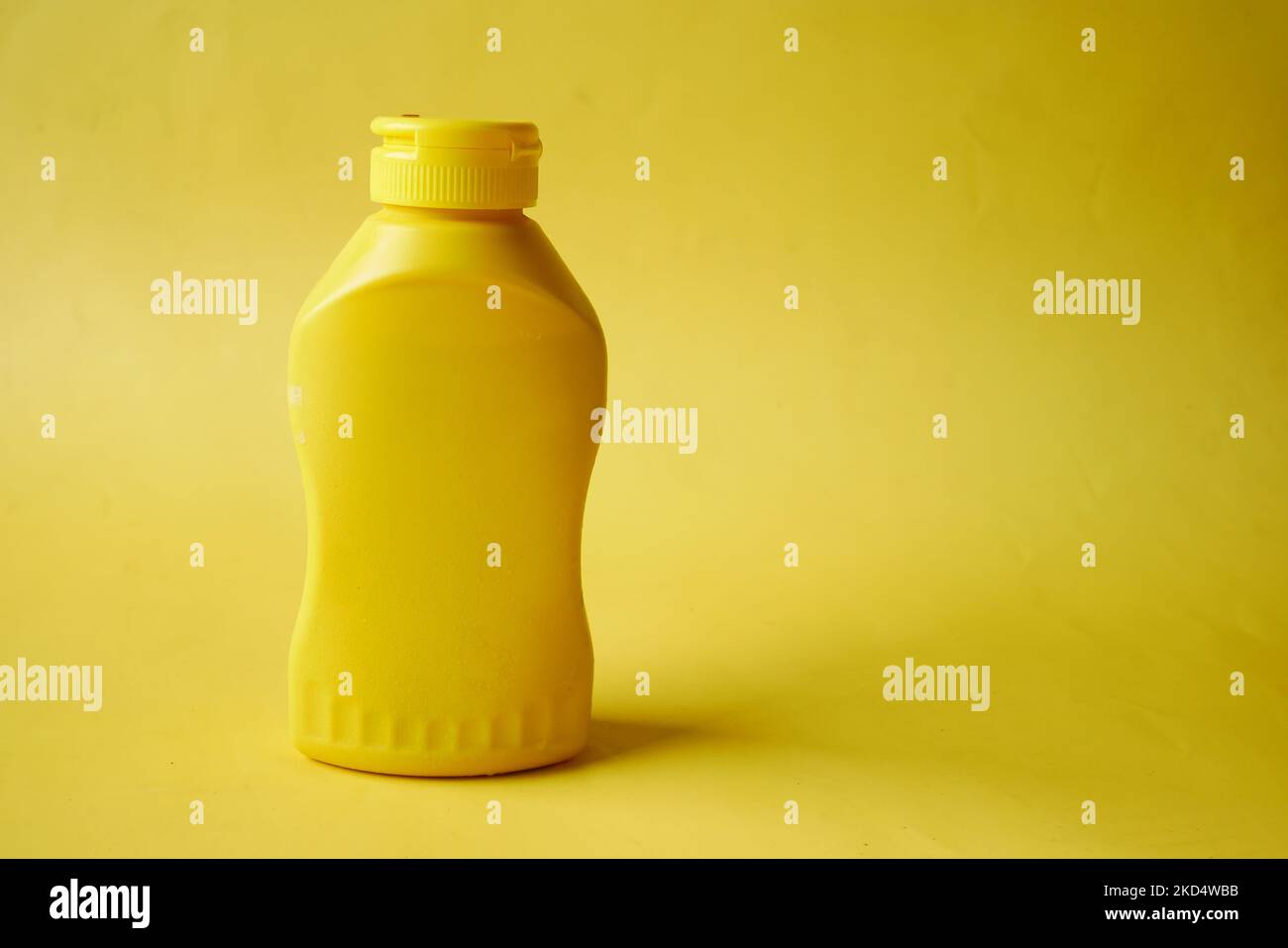 mustard mayonnaise in yellow container on yellow background Stock Photo