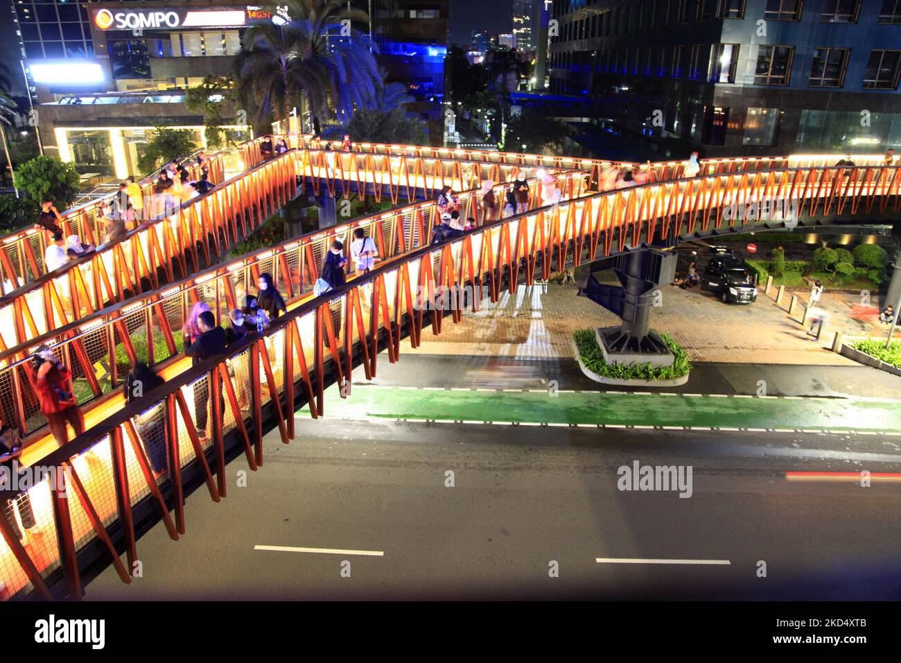 Jakartans enjoy the night view of Jakarta city on the new 'Instagramable' pedestrian bridge in Jakarta, on March 12, 2022. The Jakarta government has finished revitalizing the pedestrian bridge on Sudirman, main road, Central Jakarta, with a traditional Phinisi ship unique design. In addition to being an attraction for residents for recreation, this pedestrian bridge was also integrated with the Transjakarta bus stop, which makes it easier for pedestrians to use transportation. And on the viewing platform, there is a placard with the names of medical personnel who died while handling the Covid Stock Photo