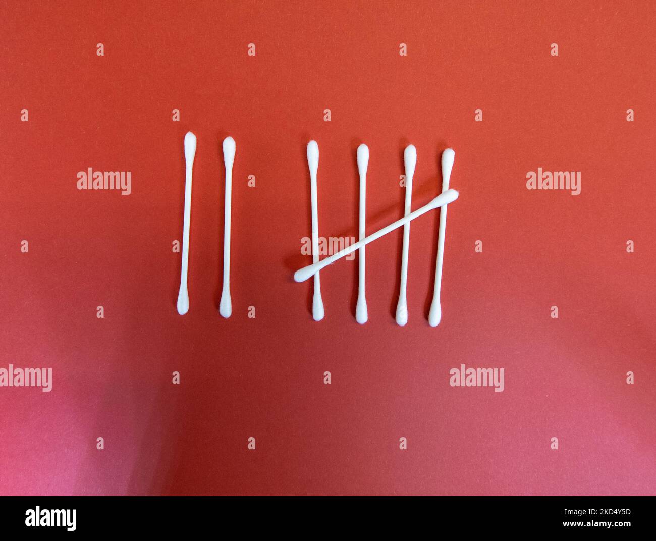 the number seven (7) in Tally marks or hash marks with clean white cotton buds isolated on a dark red background Stock Photo