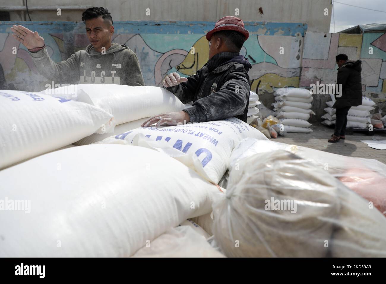 Palestinians collect food aid at a distribution center run by the United Nations Relief and Works Agency (UNRWA), in Gaza City, on March 16, 2022.- Russia's invasion of Ukraine could mean less bread on the table many cuntries in the Arab world where millions already struggle to survive. The region is heavily dependent on wheat supplies from the two countries which are now at war, and any shortages of the staple food have potential to bring unrest. (Photo by Majdi Fathi/NurPhoto) Stock Photo