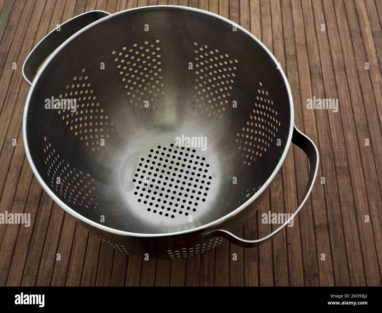 A top view of a stainless steel colander on a wooden table Stock Photo ...