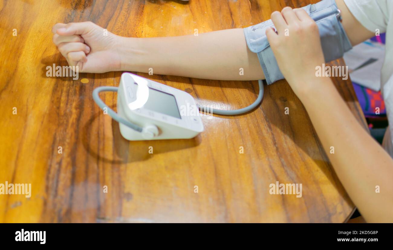 young woman measuring blood pressure and heart rate at home Stock Photo