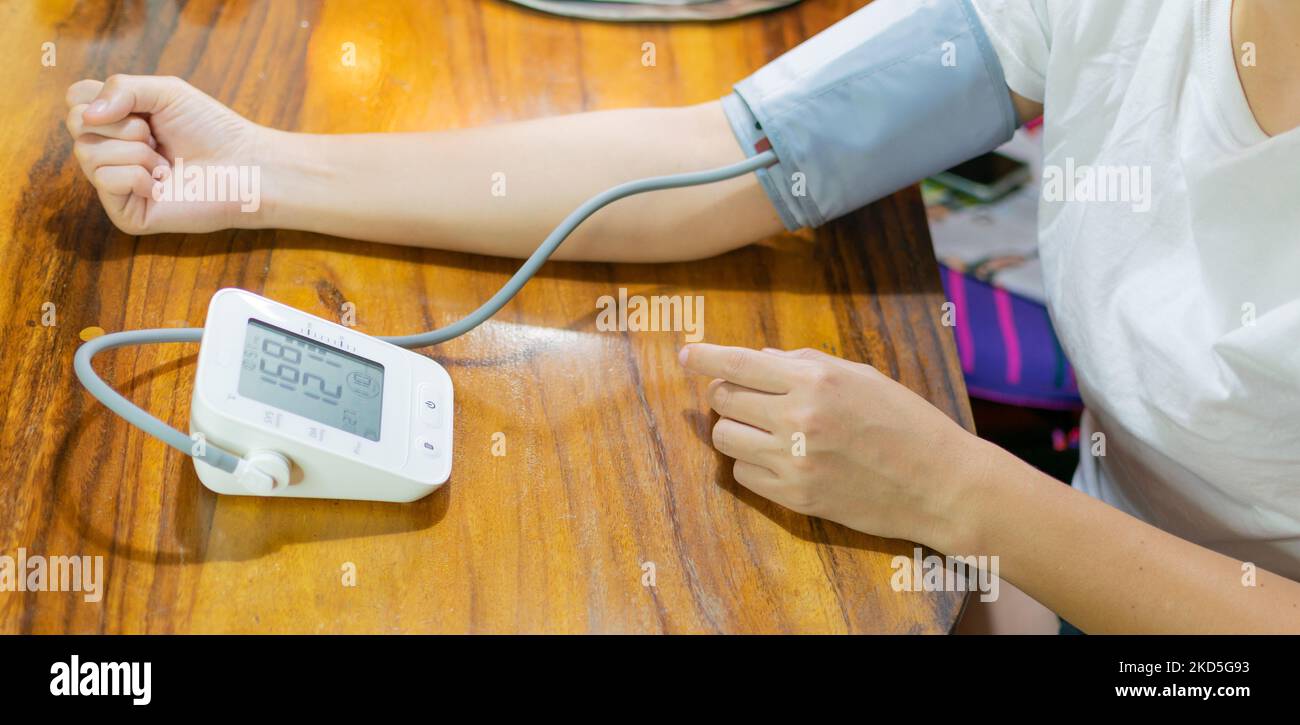 young woman measuring blood pressure and heart rate at home Stock Photo