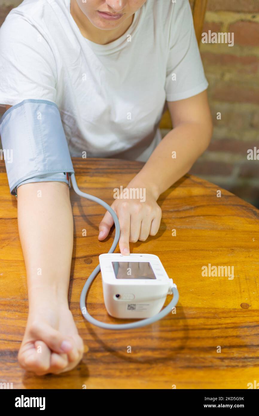young woman measuring blood pressure and heart rate at home Stock Photo
