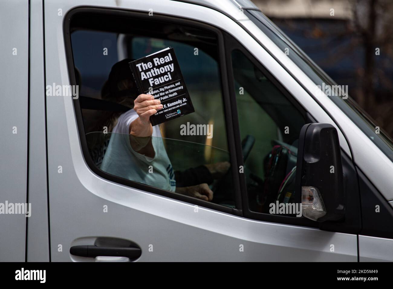 A woman holds a copy of Robert F. Kennedy Jr.'s book 'The Real Anthony Fauci' as a small convoy of truck drivers and people protesting against COVID-19-related mandates drives through Washington, D.C. on March 20, 2022 (Photo by Bryan Olin Dozier/NurPhoto) Stock Photo