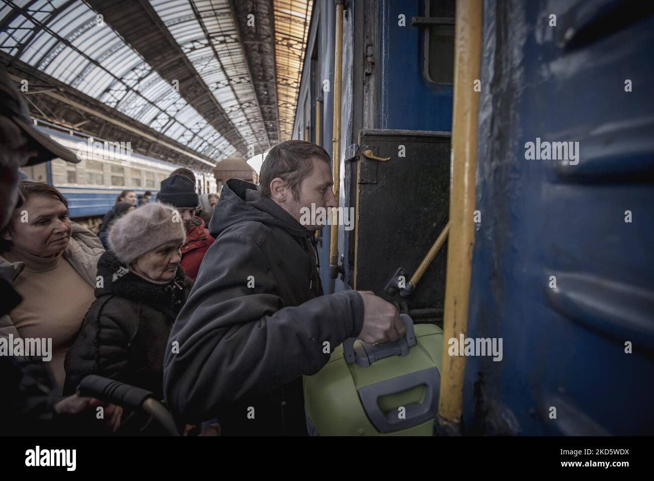 A man holding a baggage is boarding the train. People rush to get on ...