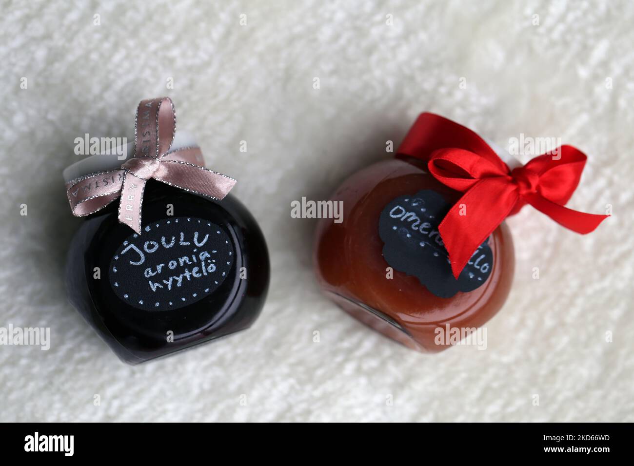 Two homemade Christmas marmelades in glass jars decorated with red bows