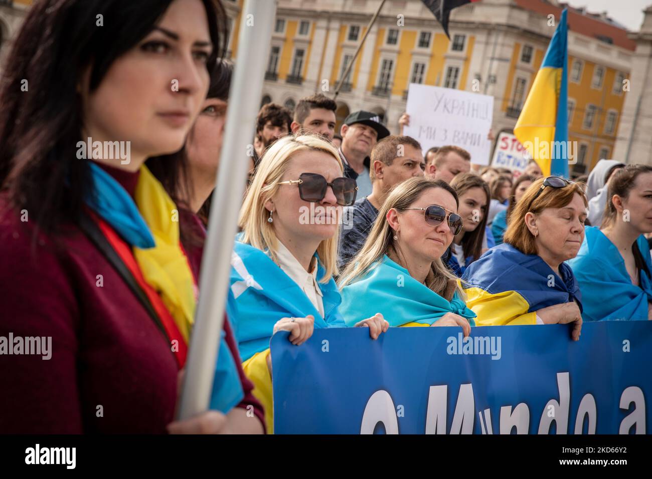 People wearing the Ukrainian flag are seen in Praca do Comercio, in Lisbon, Portugal during a demonstration to show solidarity with the people of that country following the Russian invasion on March 27, 2022. - More than 3.8 million people have fled Ukraine since Russia's invasion a month ago, UN figures showed on March 27, but the flow of refugees has slowed down markedly. The UN refugee agency, UNHCR, said 3,821,049 Ukrainians had fled the country -- an increase of 48,450 from the figures of March 26. (Photo by Manuel Romano/NurPhoto) Stock Photo