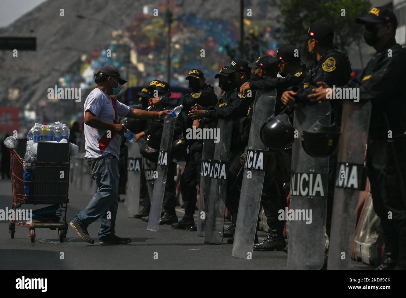 Peruvian Riot Armor A street vendor delivers bottles of water to members of Riot Police who ...