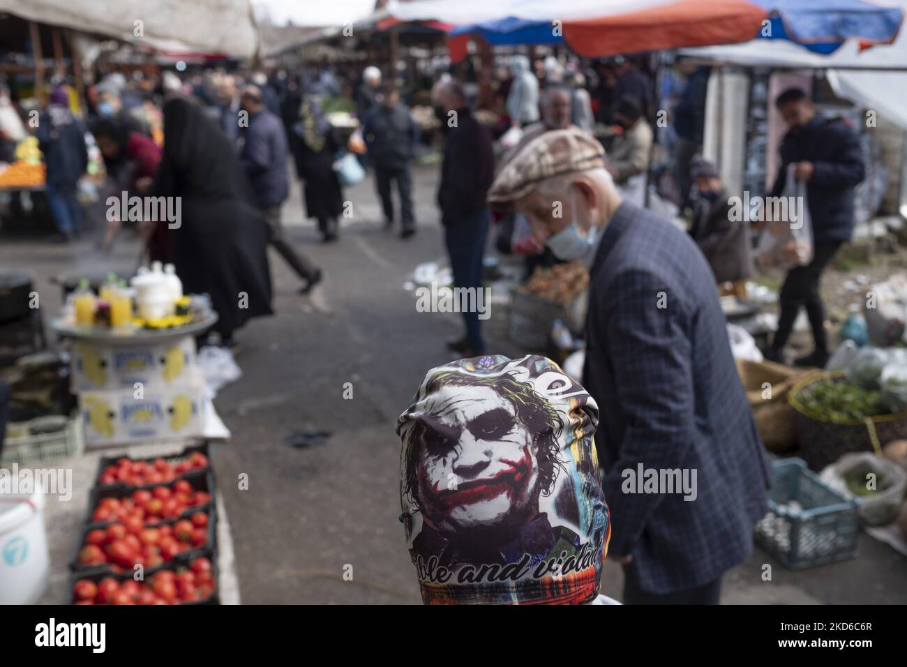 In the Basir Thursday Bazaar (Market) in the city of Astaneh-ye Ashrafiyeh in Gilan province 346 kilometers northwest of Tehran, an Iranian vendor wearing a scarf with a portrait of the American film character, Joker, on March 24, 2022. (Photo by Morteza Nikoubazl/NurPhoto) Stock Photo