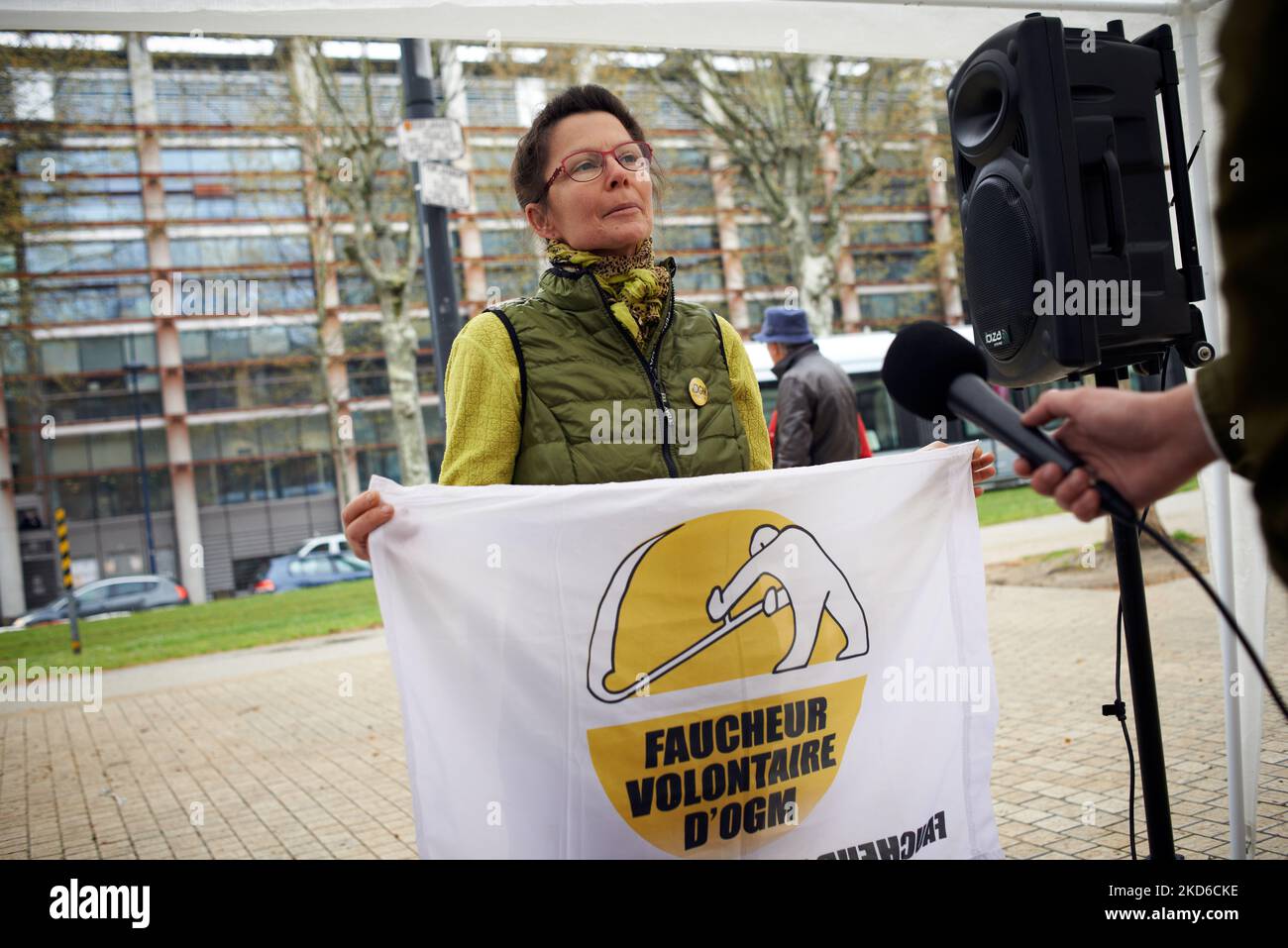 A woman, memeber of the 'Faucheurs Volontaires' speaks to the press. Three 'faucheurs volontaires' ie 'Volunteer Reapers' go on trial in Toulouse for the destruction of .75ha of cultivated fields with sunflowers. These sunflowers were part of a test for a Vegetable Variety Tolerant At Herbicides (VrTH) in 2017. The test project was called SYPPRE and made by Arvalis (cropmaker), the Beetroot Technical Institute and by Terres-Inovia. VrTH are considered by French Justice as GMOs, and GMOs are forbidden to farm in France (and the EU). Thus, the 'faucheurs volontaires' say they are entitled to des Stock Photo