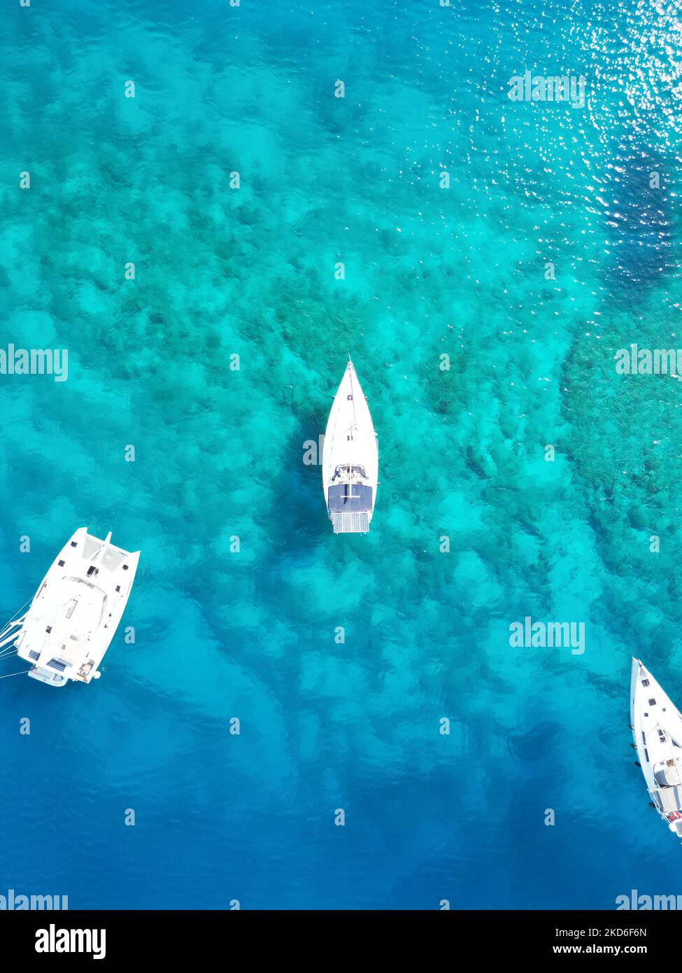 A top view of white boats in the middle of a turquoise sea with ...