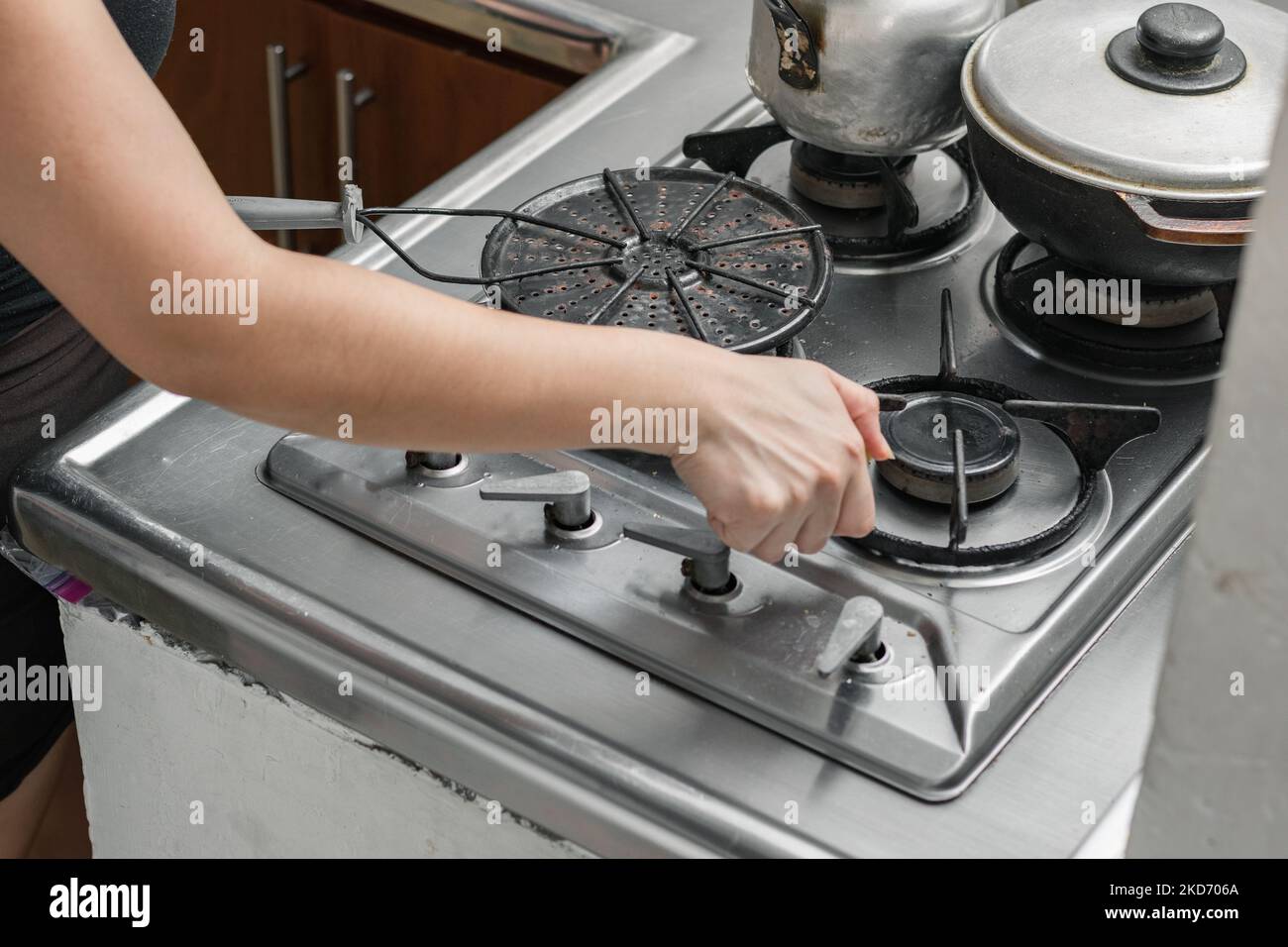 a girl's hand lighting the burner to light the gas stove and prepare ...