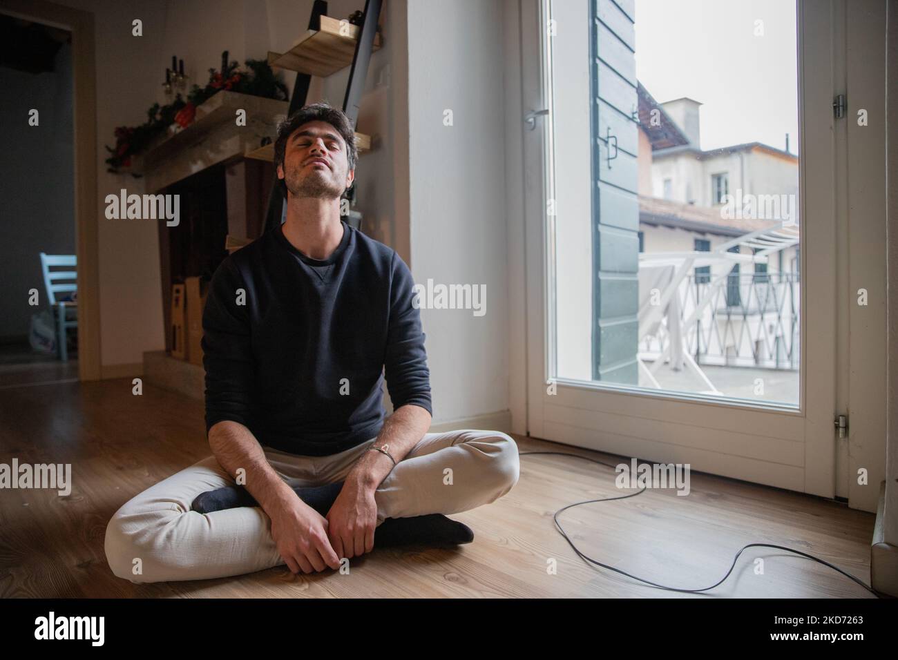 Young man sitting on the floor in meditation with crossed legs and arms ...