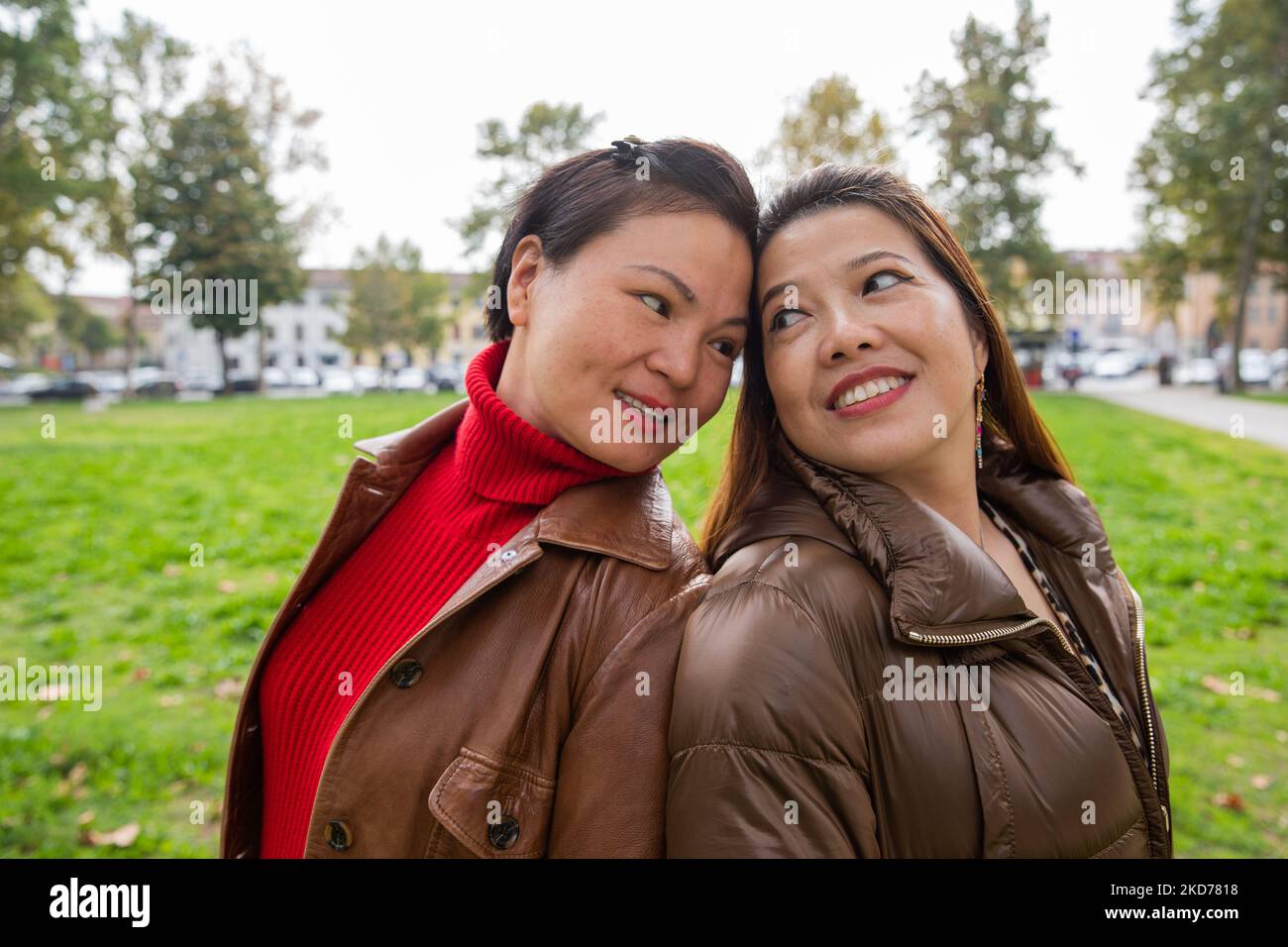 Two Chinese friends at the park back to back look into each other's eyes. Stock Photo