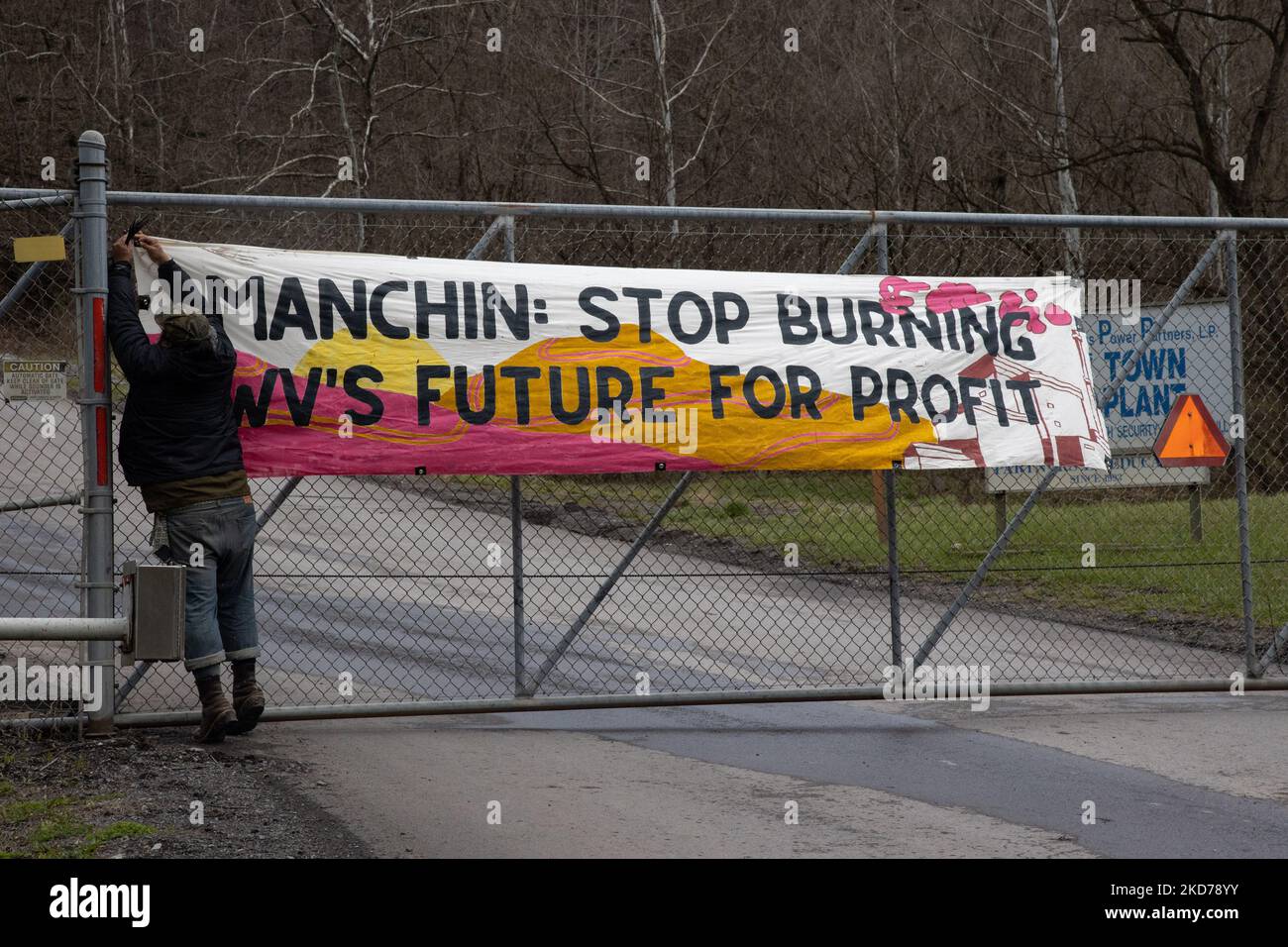 A climate activist hangs a banner at the entrance to the Grant Town