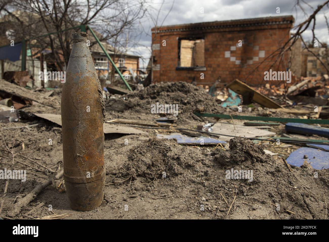 An artillery shell stands against the background of a destroyed house ...