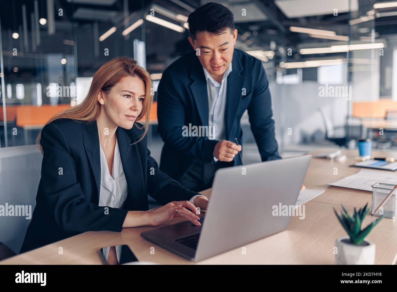 Two multiethnic coworkers working together analyzing the charts in office Stock Photo