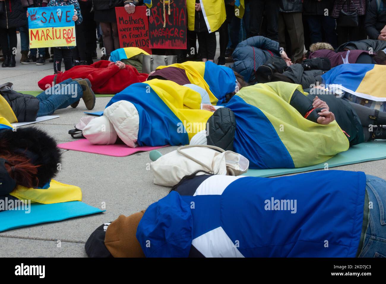 People lie on the ground, imitating the victims of the war in Ukrainian cities, in Toronto, Canada, on April 10, 2022. Mass graves of 350+ civilians were found in Kyiv suburbs of Bucha, Irpin and Moschun after the Russian army's defeat (Photo by Anatoliy Cherkasov/NurPhoto) Stock Photo