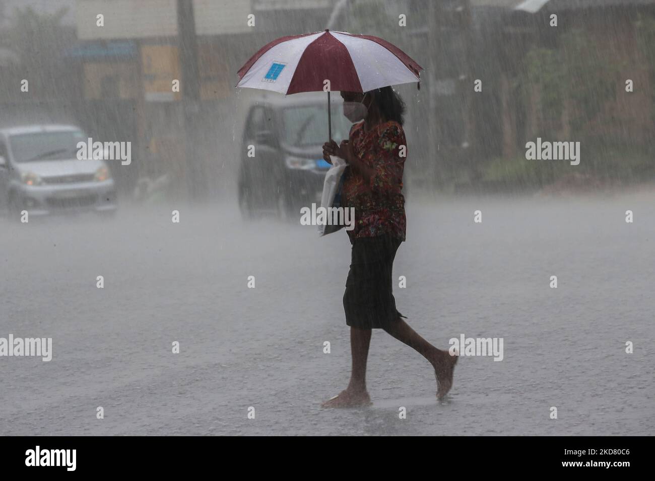 A Women walk through a road during a heavy rain shower in Colombo on