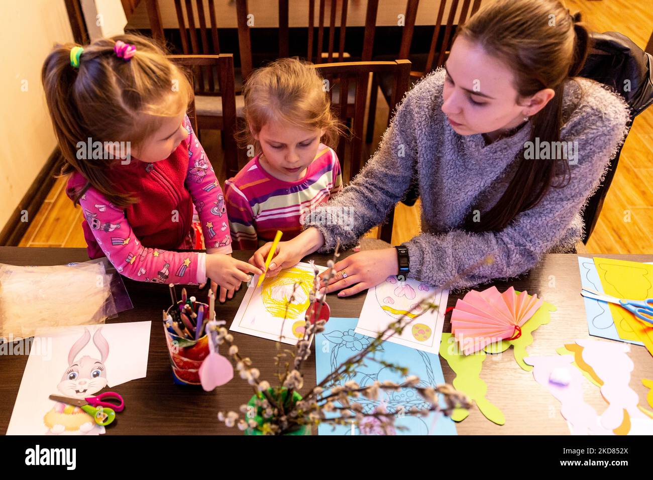 Ukrainian volunteer Krystyna prepares Easter decorations with domestic refugee children who escaped from Kharkiv area to relative safety of Nadyby, Lviv Oblast, Ukraine on April 21, 2022. Since the Russian Federation invaded Ukraine, the conflict forced over 10 million people to flee their homes, both internally and externally. Greek-Catholic Church in Nadyby near Lviv hosts dozens of mothers with children who fled the war in eastern part of Ukraine and supports many more refugees in the area. The families found shelter in the Center for the Pastoral Care of Priests and Monks in Nadyby. (Photo Stock Photo