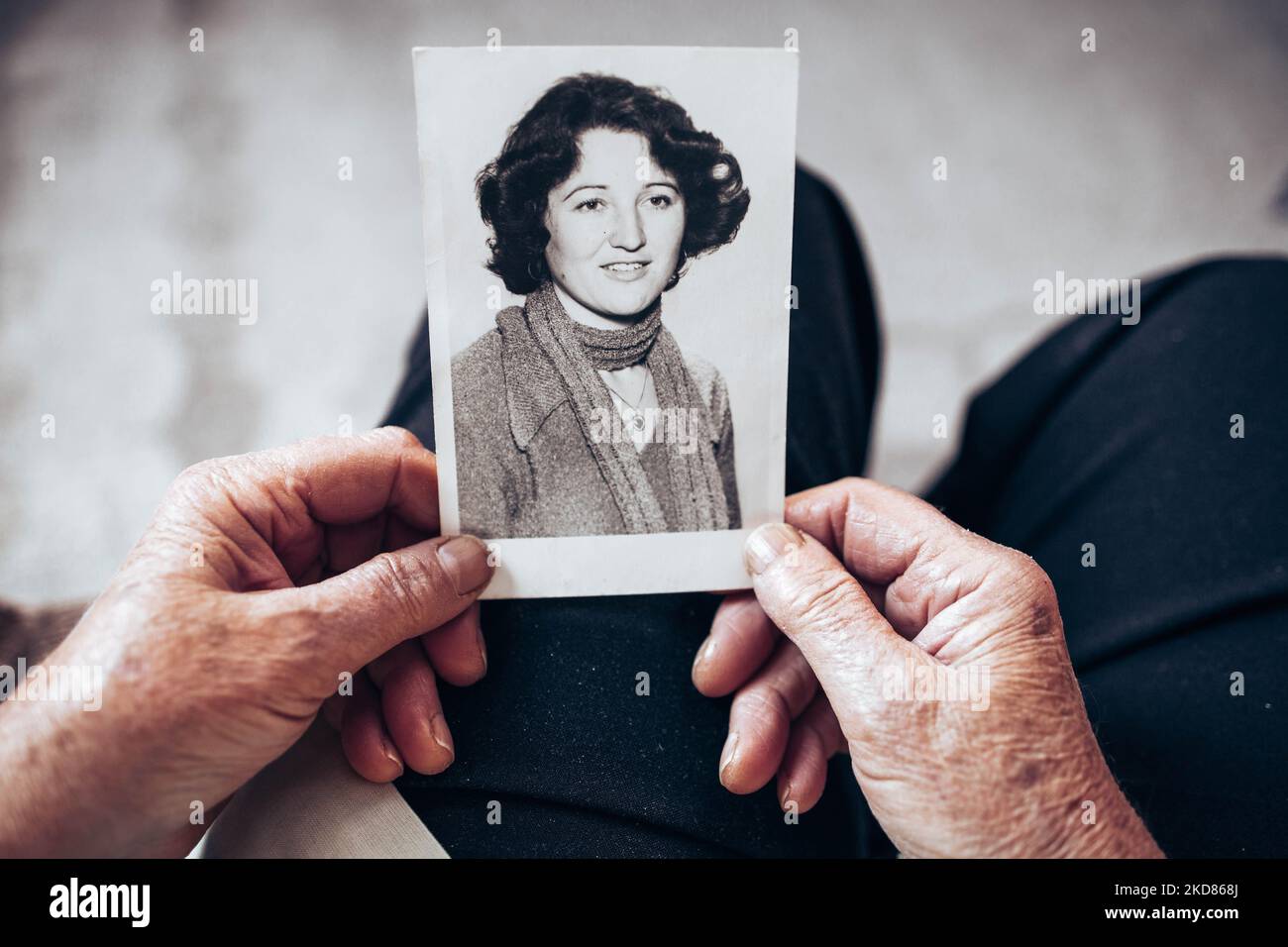 CIRCA 1970: Elderly woman hands holding vintage, black and white photo of the young woman. Passing of time concept Stock Photo