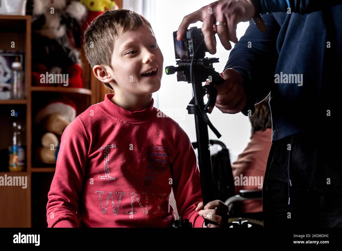 A Ukrainian girl with learning disabilities smiles as she plays with a camera provided by the photographer in a common room in a Center for women and girls with learning disabilities run by Greek Catholic church in Bukova, Lviv Oblast Ukraine on April 25, 2022. As the Russian Federation invaded Ukraine two months ago, the conflict caused that places like the Centre in Bukova become even more isolated and underfunded. (Photo by Dominika Zarzycka/NurPhoto) Stock Photo