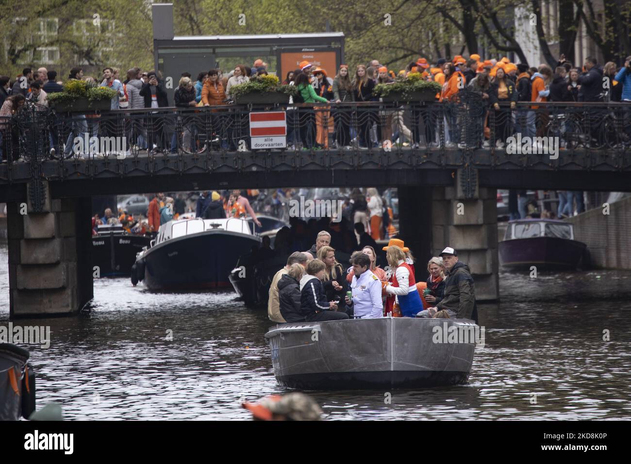 The Netherlands celebrates King's Day after two years of cancellation due to the COVID-19 Coronavirus pandemic and the lockdown restrictions and measures. Thousands of locals and visitors visited the canals of Amsterdam to celebrate with various festivities the birthday of King Willem-Alexander known as Koningsdag, a Dutch national holiday. All kind of boats and vessels are seen in the canals passing under the famous bridges and near the narrow houses of Amsterdam with people on the dancing and having fun. The boats parade down in the inner city canals while travelers gather on the streets. Du Stock Photo