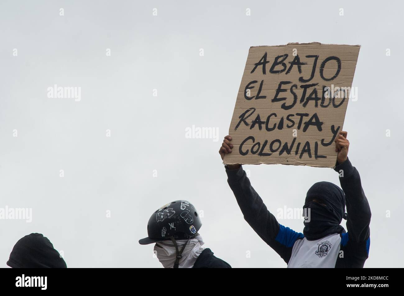 A demonstrator holds a sign that reads 'Down with the racist and colonial state' during the 28 of April commemorative demonstrations against the government of president Ivan Duque and violence at Universidad Nacional de Colombia, demonstrators took the closed campus of the University to clash. On April 28, 2022, in Bogota, Colombia (Photo by Sebastian Barros/NurPhoto) Stock Photo