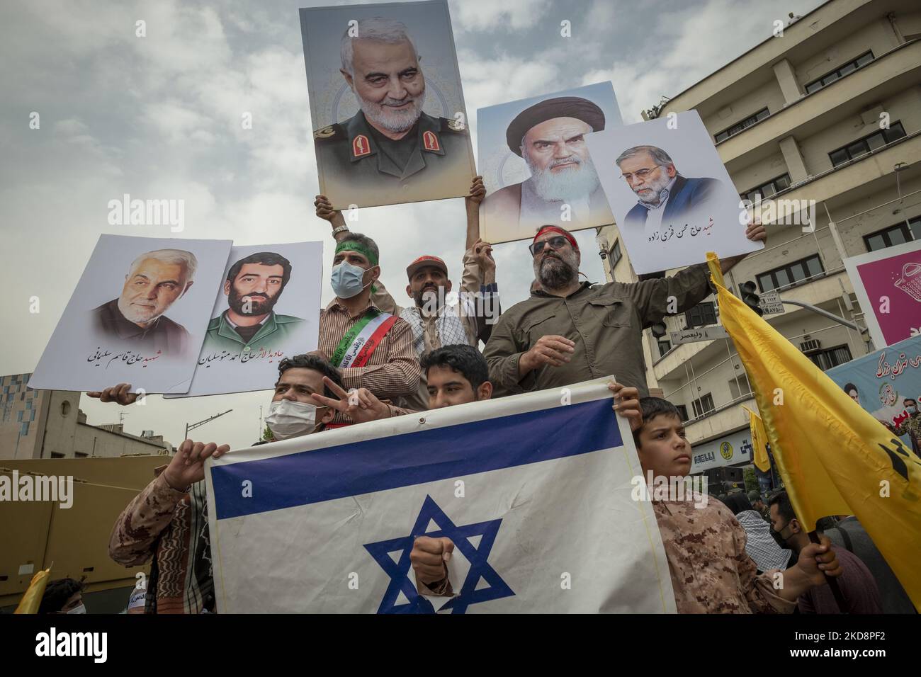 Iranian demonstrators hold-up portraits of the former commander of Iran’s Islamic Revolutionary Guard Corps’ (IRGC) Quds Force, General Qasem Soleimani (C), Iranian Nuclear scientist, Mohsen Fakhrizadeh (R), and Iran’s Late Leader Ayatollah Ruhollah Khomeini while standing behind a torn Israeli flag during a rally commemorating the International Quds Day, also known as the Jerusalem day, on April 29, 2022. (Photo by Morteza Nikoubazl/NurPhoto) Stock Photo