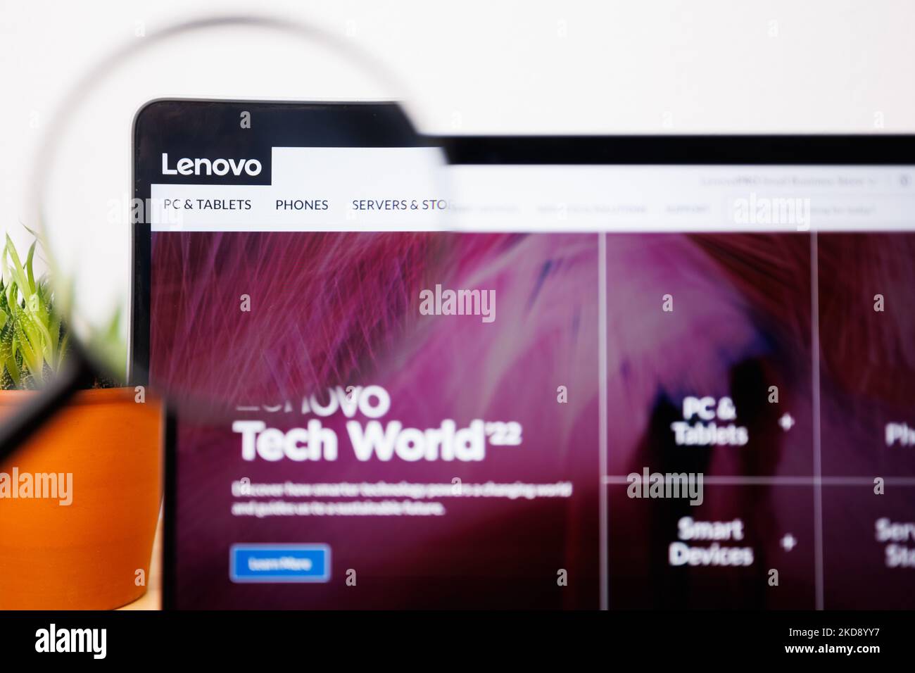 A lenovo Logo under a magnifying glass. lenovo Website on Laptop screen Stock Photo