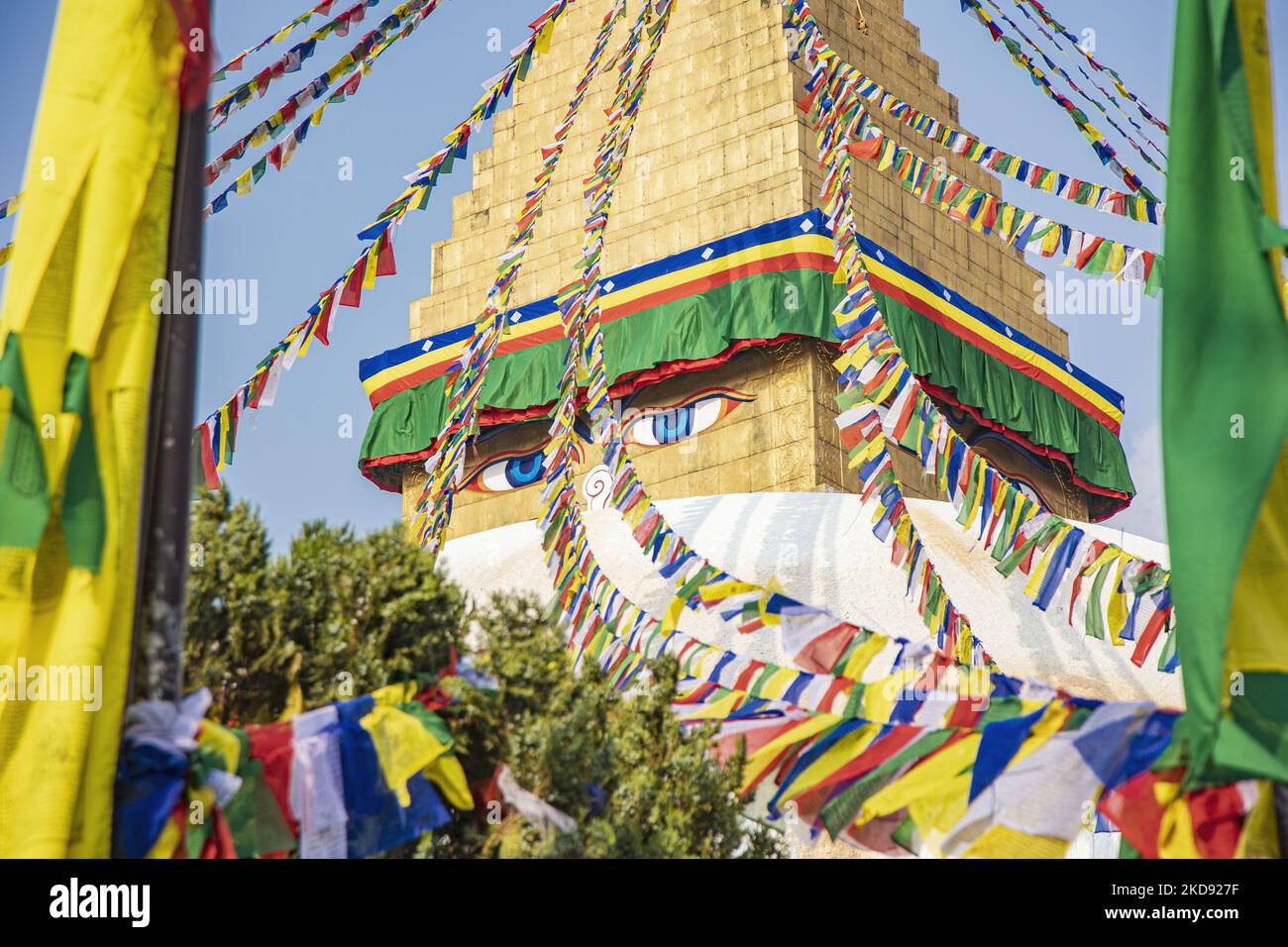 Closeup at the golden top with the Eyes of the stupa, where the praying flags begin. Boudhanath or Bouddha Stupa in Kathmandu a UNESCO World Heritage Site and a legendary place for the Newar and Tibetan Buddhist mythology with the golden part having the Eyes of Boudhanath and the praying flags. One of the most popular tourist attraction in Kathmandu, the mandala makes it one of the largest spherical stupas in Nepal and the world. The Stupa was damaged in the 2015 April earthquake. The Stupa is located on the ancient trade route from Tibet, and the Tibetan Refugees after the 1950s decided to li Stock Photo
