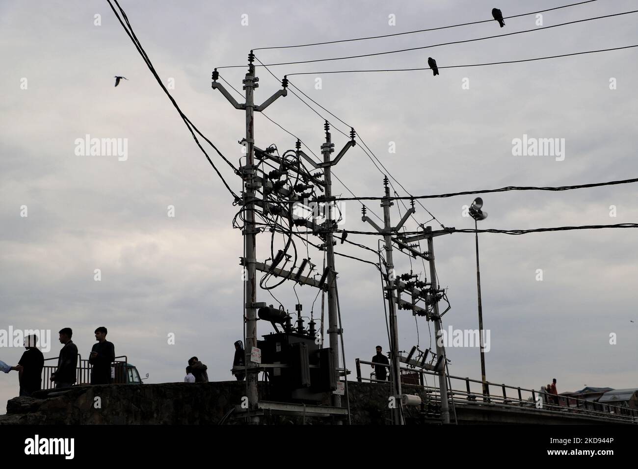People walk as Electricity Transformers are installed in Sopore