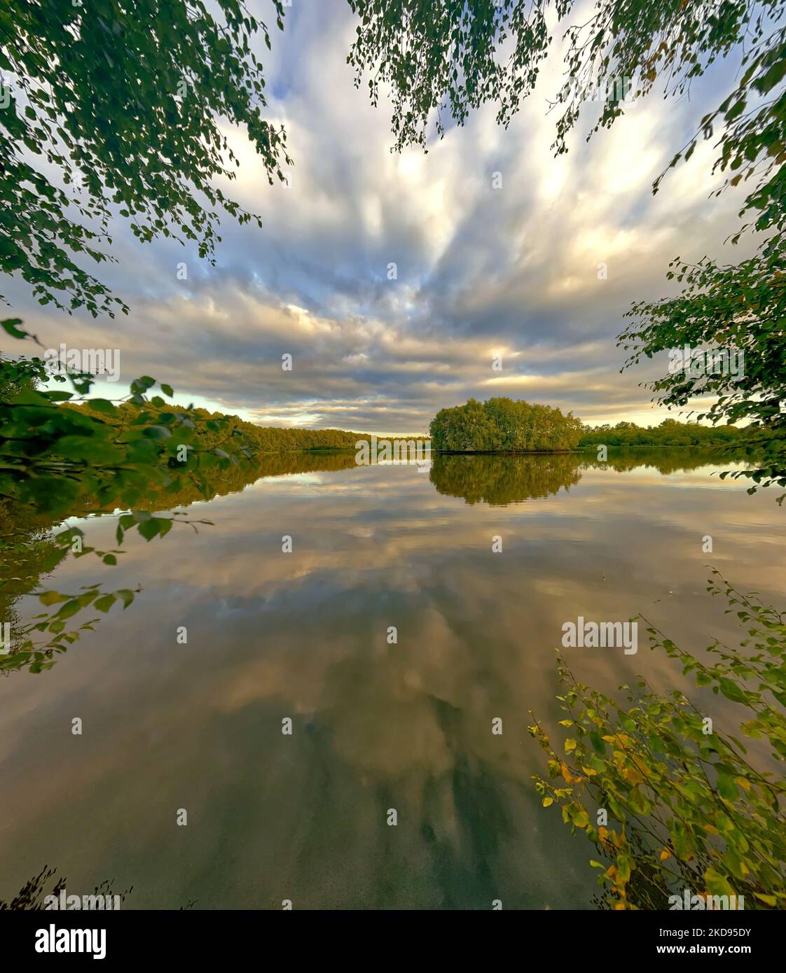 A beautiful scenery of a lake surrounded by greenery under cloudy sky ...
