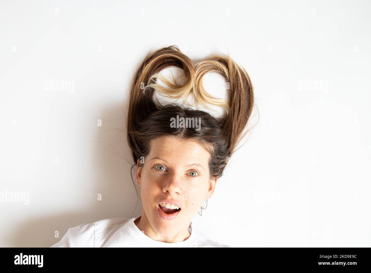 A girl with long hair and a smile lies on a white background, an